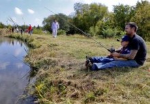 CHRIS NEAL/THE CAPITAL-JOURNAL Dusty Roberts and his 6-year-old son, Aiden, of Topeka, wait for a fish to bite while fishing at Caterpillar Pond on the Falley Scout Reservation grounds in Oskaloosa. The pond had been stocked with fish a few days before the adventure camp.